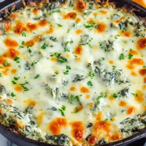 creamy baked spinach cheese dip with melted mozzarella and parsley topping in skillet